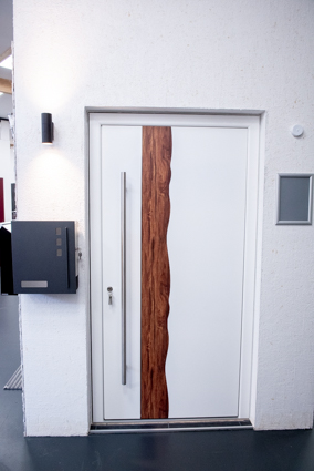 Eine weiße Eingangstür mit einem Längststreifen aus Holz montiert in der Ausstellung von Neumeyer in Krefeld.